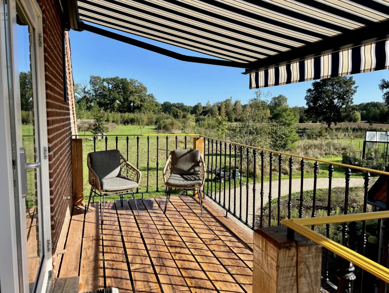 Balkon met loungestoelen en uitzicht over de weide en poel