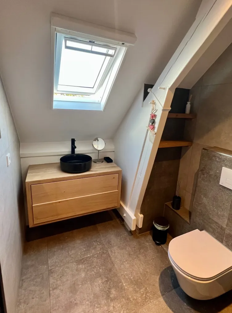 Badkamer met zwarte waskom, houten meubel en toilet