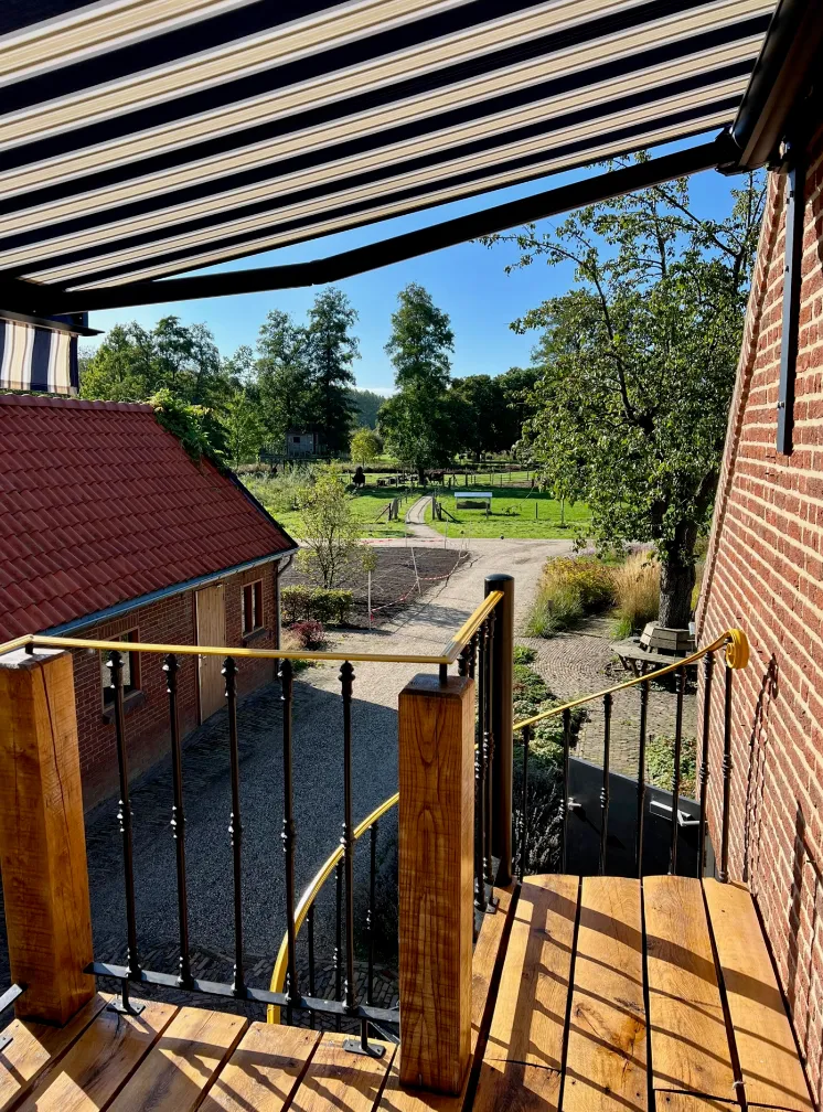 Uitzicht vanaf het balkon over de tuin en het achterliggende landschap