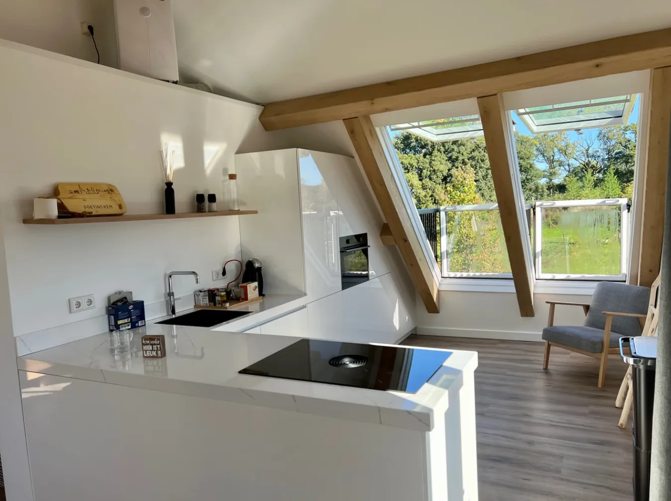 Strakke witte keuken met inductiekookplaat en uitzicht door de dakramen